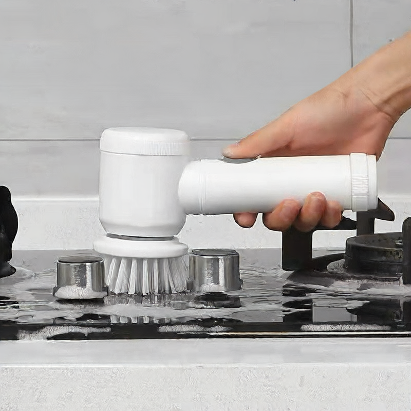 Person using a white kitchen cleaning brush on a stovetop.