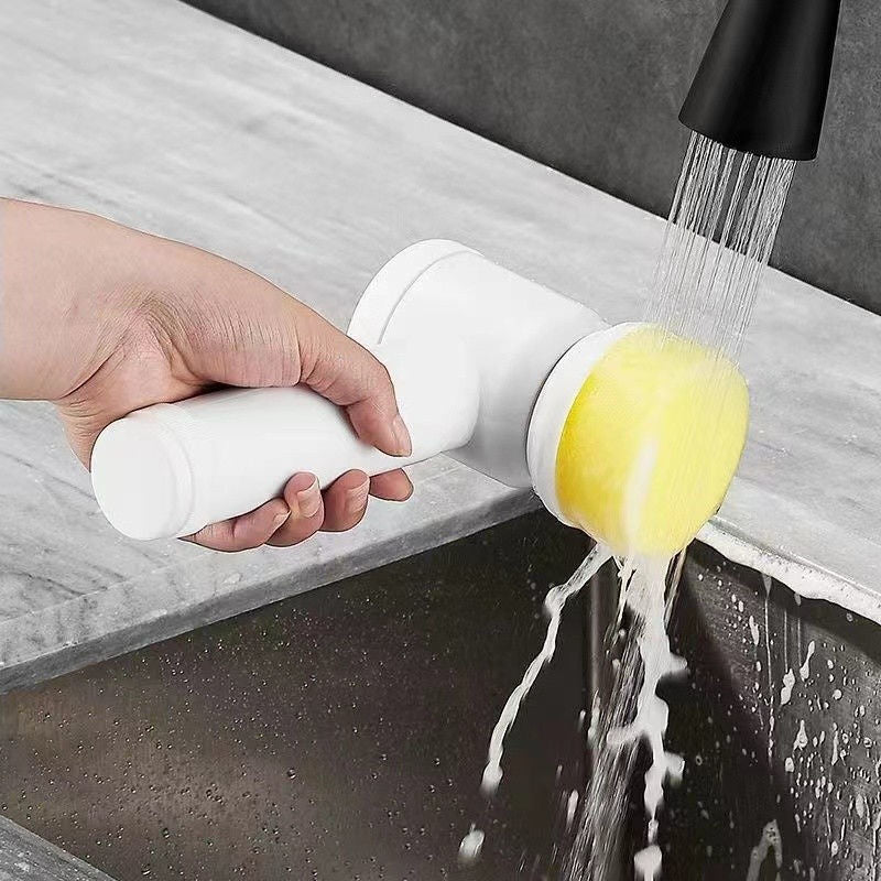 Hand washing a yellow sponge with a white handle under running water in a kitchen sink.